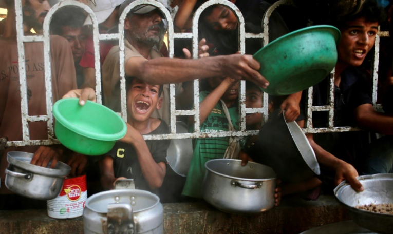 Des Palestiniens dont un enfant en pleurs se bousculent pour recevoir un repas chaud auprès d'une organisation caritative locale à Khan Younès, dans le sud de la bande de Gaza, le 22 juillet 2025. ( AFP / - )