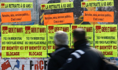 Des gens passent devant des affiches à Bouguenais appelant à la grève et à des manifestations contre le plan de réforme des retraites du gouvernement