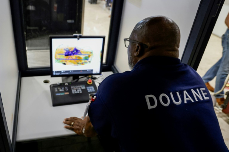 Un douanier français scanne le bagage d'un passager se rendant à Paris à l'aéroport international Félix-Eboué de Cayenne, le 24 mars 2024 ( AFP / Ludovic MARIN )