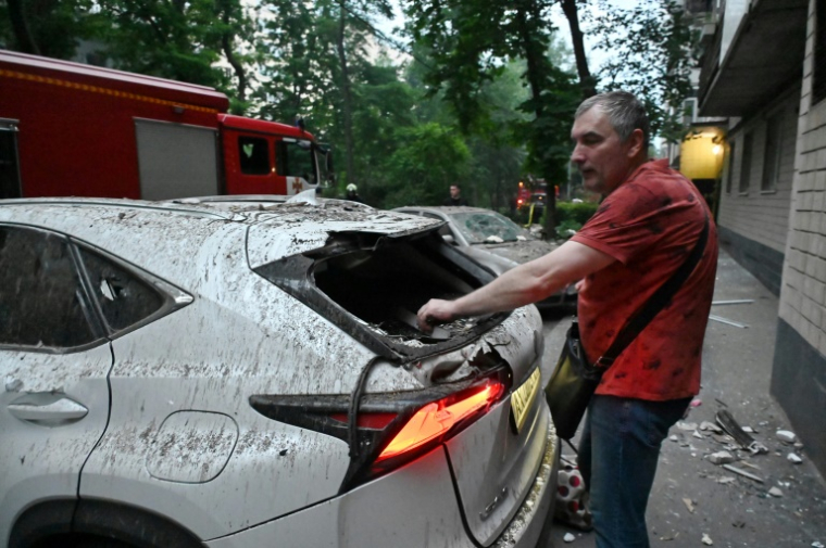 Un homme retrouve sa voiture endommagée après une série d'attaques russes contre la ville de Kharkiv, dans l'est de l'Ukraine, le 7 juin 2025 ( AFP / SERGEY BOBOK )