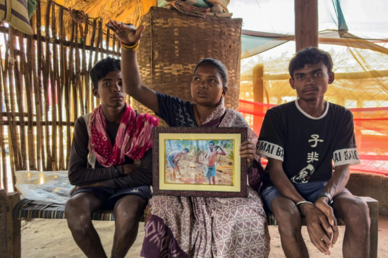 Somari Negi (c), veuve de Rameshwar Negi, tué en 2024 par les paramilitaires qui le soupçonnaientt d'être un rebelle maoïste, montre une photo de son mari, aux côtés de ses fils, à Marda, dans le district de Bastar de l'Etat de Chhattisgarh, le 14 mars 2025 dans le centre de l'Inde ( AFP / Jalees ANDRABI )