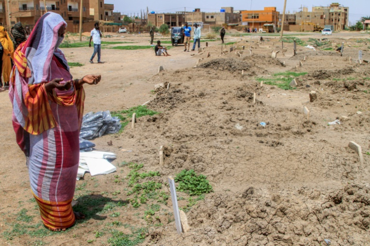 Une femme récite une prière devant des tombes dans le quartier d'Al-Azhari dans la banlieue de Khartoum, le 2 août 2025 ( AFP / Ebrahim Hamid )