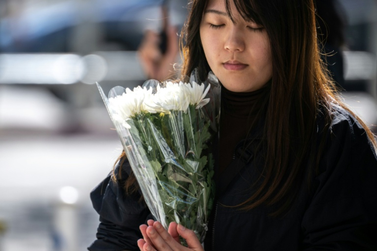 Une femme se recueille le 29 novembre 2025 devant le complexe résidentiel de Wang Fuk Court à Hong Kong  la suite de l’incendie meurtrier survenu trois jours auparavant ( AFP / Philip FONG )