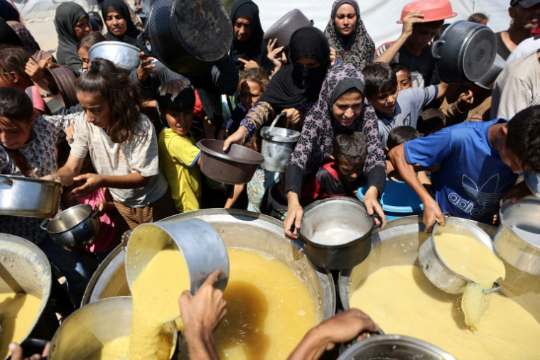 Des Palestiniens reçoivent de la soupe aux lentilles à un point de distribution de nourriture dans la ville de Gaza, le 1er août 2025 ( AFP / Omar AL-QATTAA )