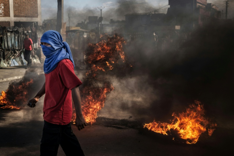 Un manifestant devant des barricades en feu lors d'affrontements avec les forces de sécurité à Antananarivo, le 7 octobre 2025 ( AFP / Luis TATO )