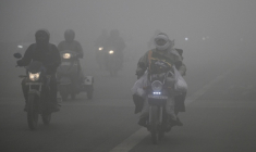 Des deux-roues circulent au milieu d'un épais brouillard de pollution à New Delhi, le 27 décembre 2025 ( AFP / Arun SANKAR )