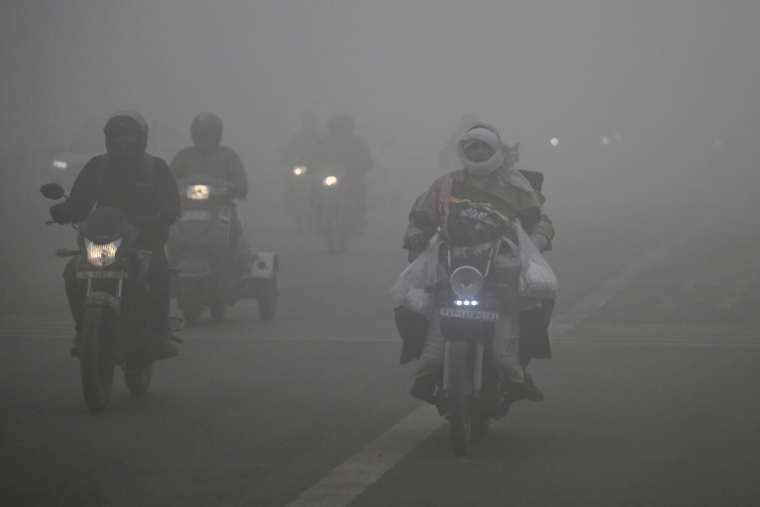 Des deux-roues circulent au milieu d'un épais brouillard de pollution à New Delhi, le 27 décembre 2025 ( AFP / Arun SANKAR )