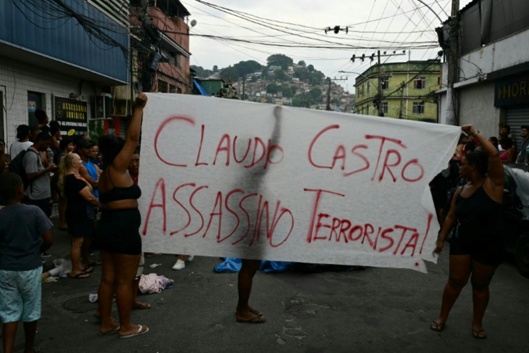 Des habitants d'une favela brandissent une pancarte qualifiant d'"Assassin terroriste" le gouverneur de l'Etat de Rio, Claudio Castro, le 29 octobre 2025 ( AFP / Pablo PORCIUNCULA )