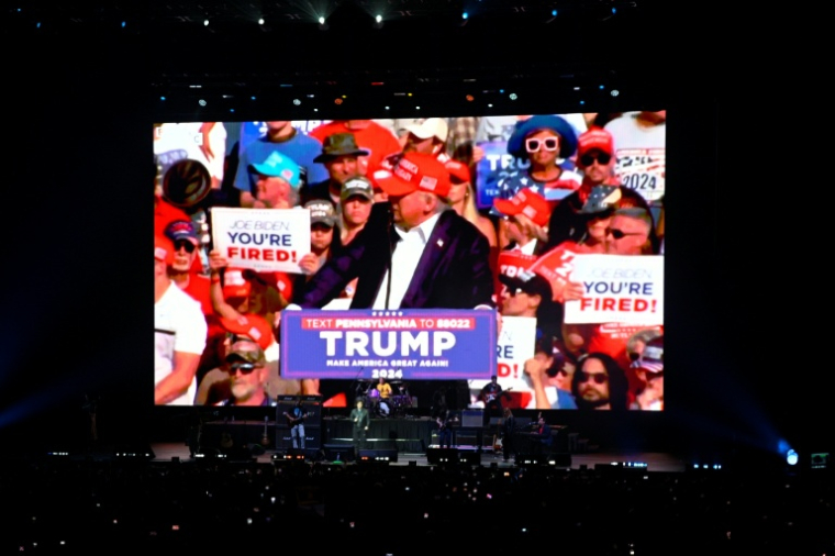 Le président argentin Javier Milei sur scène alors que des images du président américain Donald Trump sont projetées sur un écran géant lors du lancement de son nouveau livre, "La fabrique du miracle", à Buenos Aires, le 6 octobre 2025 ( AFP / LUIS ROBAYO )