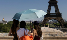 Des touristes se protègent du soleil sous un paraplluie devant la Tour Eiffel lors d'une vague de chaleur à Paris, le 27 mai 2026 ( AFP / JOEL SAGET )