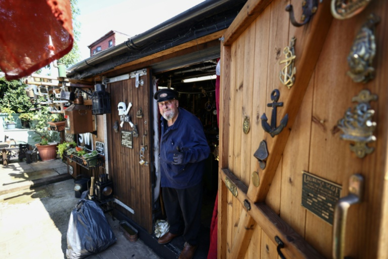 Peter McLaughlin à l'entrée de son abri de jardin, aménagé pour reproduire la chaufferie d'un navire, à l'arrière de sa maison à Londres, le 31 juillet 2026 ( AFP / Henry NICHOLLS )