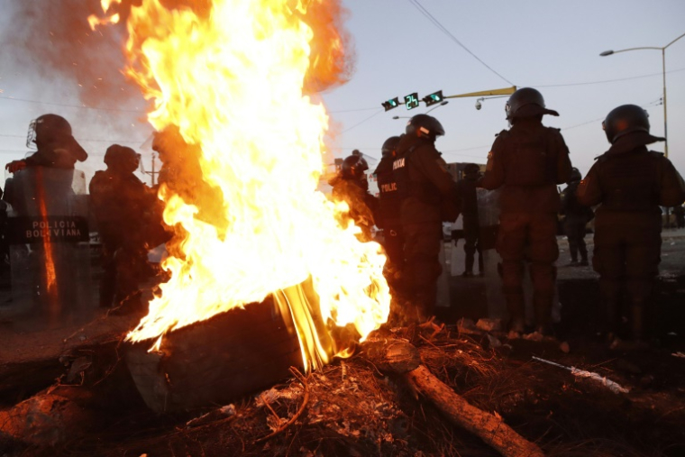 Des policiers boliviens près d'une barricade en feu montée par des partisans de l'ex-président Evo Morales, le 6 juin 2025 à Vinto ( AFP / David FLORES )