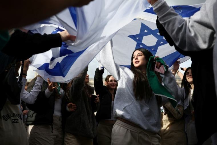 Des personnes dansent sous des drapeaux israéliens lors d'un événement commémoratif organisé par la communauté juive pour honorer les vies perdues lors de l'attaque du Hamas le 7 octobre 2023, à Londres, le 5 octobre 2025 ( AFP / HENRY NICHOLLS )