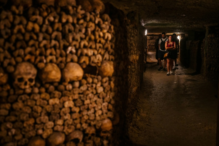 Des touristes visitent les catacombes de Paris, le 12 août 2025 ( AFP / Dimitar DILKOFF )