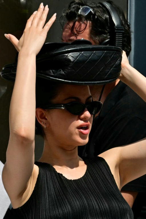 A guest protects herself from the sun with her purse before the Thom Browne collection show at Milan's Fashion Week Menswear Spring/Summer 2027, in Milan on June 22, 2026 ( AFP / Stefano RELLANDINI )