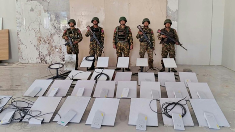 Photo du 20 octobre 2025, diffusée le 22 octobre 2025 par l'équipe d'information militaire de Birmanie, de soldats birmans debout à côté d'appareils Starlink saisis lors d'un raid sur le centre d'escroquerie en ligne KK Park à Myawaddy ( Equipe d'information militaire de Birmanie / Handout )