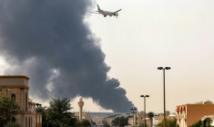 Un avion de la compagnie Emirates s'apprête à atterrir à l'aéroport de Dubaï d'où s'élève une épaisse fumée  après l'incendie d'un réservoir, le 16 mar 2026 au Emirats arabes unis ( AFP / - )
