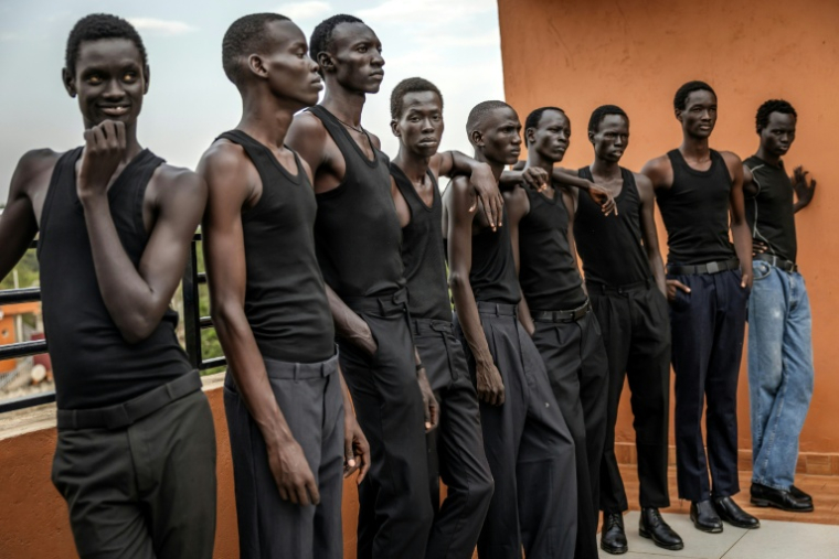 Des jeunes mannequins ,écoutent les instructions d'un coach pour apprendre à défiler sur le toit des bureaux de l'agence Jubalicious à Juba, le 20 février 2026 au Soudan du Sud ( AFP / Luis TATO )
