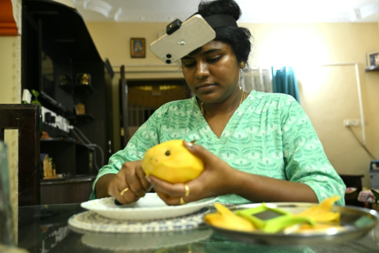 Nagireddy Sriramyachandra filme avec un téléphone ses gestes pendant qu'elle coupe une mangue pour entraîner un futur robot dopé à l'IA, le 15 mai 2026 à Madras, en Inde ( AFP / R.Satish BABU )