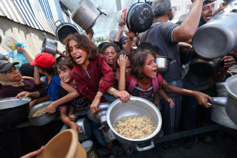Des enfants palestiniens se bousculent pour recevoir un repas chaud à Nousseirat, dans la bande de Gaza, le 4 septembre 2025 ( AFP / Eyad BABA )