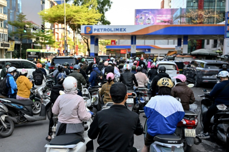 Des motocyclistes font la queue pour faire le plein d'essence dans une station-service à Hanoï, le 10 mars 2026 au Vietnam ( AFP / Nhac NGUYEN )