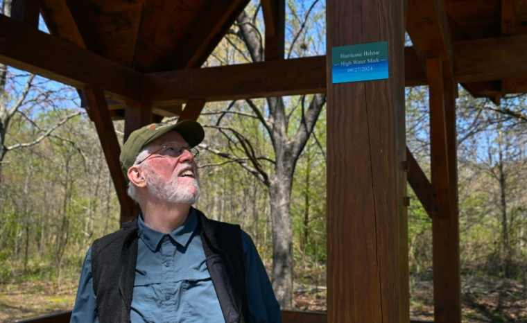 Tony Dunn à côté d'un marqueur indiquant le niveau maximal des inondations provoquées par l'ouragan Helene en septembre 2024, lors d'une interview avec l'AFP dans un parc de Flat Rock, en Caroline du Nord, le 9 avril 2026 ( AFP / Peter Zay )