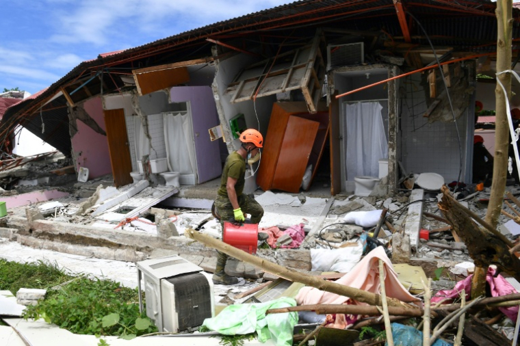 Un sauveteur arrive devant un bâtiment effondré où la disparition de trois personnes a été signalée après un séism, dans la ville de Bogo (Philippines), le 1er octobre 2025 ( AFP / TED ALJIBE )