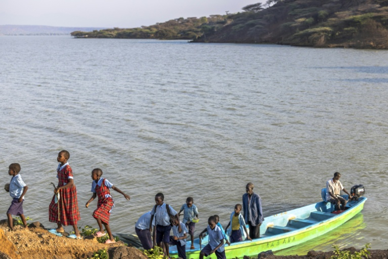 Des élèves rejoignent leur école en bateau, le 28 juillet 2026, sur le lac Bogoria, au Kenya, dont la montée des eaux a submergé le passage habituellement emprunté ( AFP / Tony KARUMBA )
