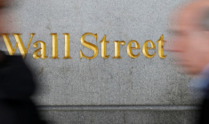 Des gens devant un panneau de Wall Street près de la Bourse de New York à New York