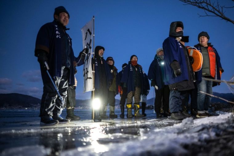 Des fidèles du culte shinto sur le lac Suwa, le 29 janvier 2026 à Nagano, dans le centre du Japon  ( AFP / Philip FONG )