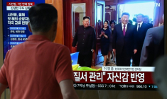 Un homme passe devant un écran de télévision diffusant un journal télévisé avec des images d'archives de la rencontre de 2019 entre le président chinois Xi Jinping et le dirigeant nord-coréen Kim Jong Un, dans une gare de Séoul, le 8 juin 2026 ( AFP / Jung Yeon-je )