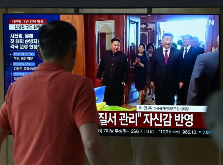 Un homme passe devant un écran de télévision diffusant un journal télévisé avec des images d'archives de la rencontre de 2019 entre le président chinois Xi Jinping et le dirigeant nord-coréen Kim Jong Un, dans une gare de Séoul, le 8 juin 2026 ( AFP / Jung Yeon-je )