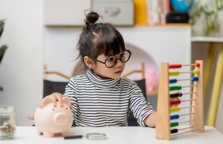 Une petite fille économise pour plus tard. (Crédits: Adobe Stock)