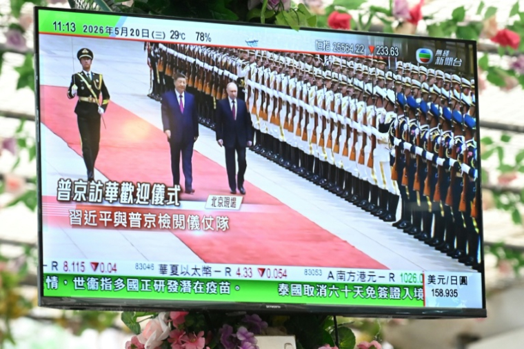 Un poste de télévision dans un restaurant de Hong Kong diffuse des images du président chinois Xi Jinping accueillant à Pékin son homologue russe Vladimir Poutine, le 20 mai 2026 ( AFP / Peter PARKS )