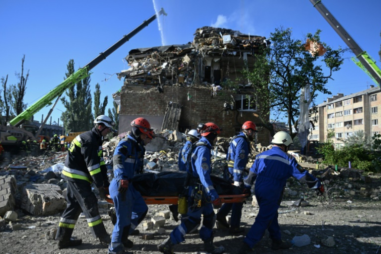 Des sauveteurs ukrainiens transportent le corps d'une victime près d'un immeuble résidentiel fortement endomagé lors d'une attaque massive de drones et de missiles russes sur Kiev, le 28 août 2025 ( AFP / Genya SAVILOV )