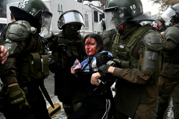 La police antiémeute interpelle un manifestant lors d'une marche étudiante contre les coupes dans les dépenses sociales décidées par le président chilien José Antonio Kast, à Santiago, le 3 juin 2026 ( AFP / RODRIGO ARANGUA )
