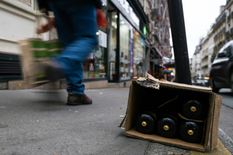 Un carton de bouteilles de protoxyde d'azote abandonné dans une rue de Paris, le 15 janvier 2026 ( AFP / Julie SEBADELHA )