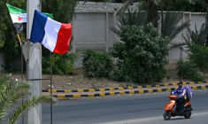 Un motocycliste passe devant des drapeaux syrien et français déployés le long de la route menant à l'aéroport, le 6 juillet 2026 à Damas avant une visite du président Emmanuel Macron ( AFP / LOUAI BESHARA )
