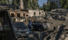 Une femme se tient près de voitures détruites et de bâtiments endommagés après une frappe russe à Kiev le 20 août 2026 ( AFP / Roman PILIPEY )
