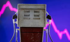 Une maquette de pompe à essence devant un graphique d'actions en baisse