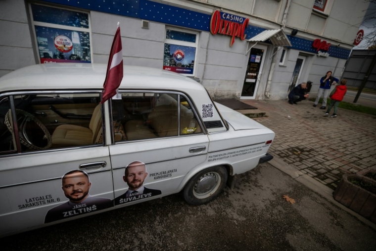 Une voiture ornée de photos des candidats du parti Progresivie (Progressistes) pendant la fête des moissons à Rezekne, en Lettonie, le 27 septembre 2026 ( AFP / Wojtek RADWANSKI )