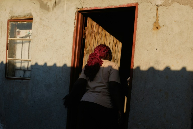 La travailleuse du sexe Sharon Mukakanhanga entre dans un logement partagé avec deux autres collègues, dans le quartier informel d'Epworth à Harare, le 28 août 2025 au Zimbabwe ( AFP / Jekesai NJIKIZANA )