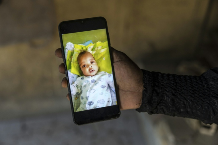 Mariam Soumah montre une photo de sa fille Sabina sur son téléphone, le 29 décembre 2025 à Conakry ( AFP / PATRICK MEINHARDT )