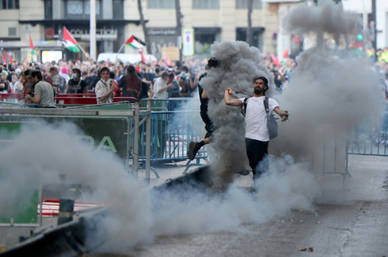 Un homme renvoie une grenade lacrymogène vers la police, après l'invasion des rues par des manifestants propalestiniens pendant la 21e et dernière étape du Tour d'Espagne cycliste, le 14 septembre 2025 ( AFP / Thomas COEX )