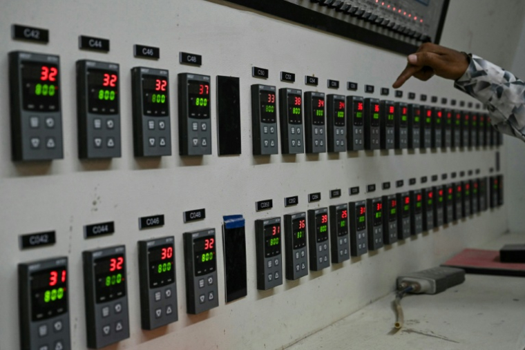 Un superviseur montre un panneau de contrôle affichant les relevés de température d'un four à propane hors service dans une usine de fabrication de carreaux de céramique, qui reste fermée, le 26 mars 2026 à Morbi, en Inde ( AFP / Indranil MUKHERJEE )