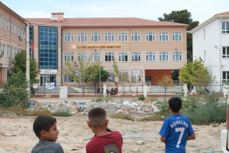 Des enfants regardent un lycée professionnel où un adolescent a ouvert le feu à Turgutlu, dans l'ouest de la Turquie, le 22 septembre 2026 ( AFP / Ilker ERAY )