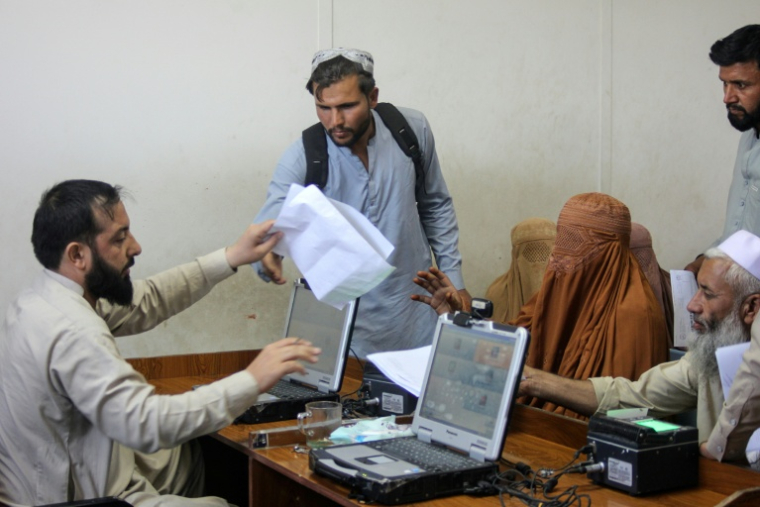 Un fonctionnaire du ministère afghan des Affaires migratoires enregistre les documents des rapatriés expulsés du Pakistan, au camp d'Omari, près du poste-frontière de Torkham, le 25 juin 2026 ( AFP / Aimal ZAHIR )