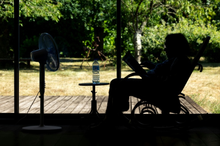 Une personne âgée assise face à un ventilateur à Pont-Audemer, dans l'Euroe, le 12 juillet 2026 lors d'une vague de chaleur en France ( AFP / JOEL SAGET )