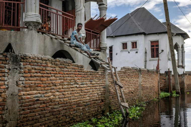 Une femme est assise sur une échelle lui servant à rejoindre sa maison dans une zone inondée à Gatumba, au Burundi, près du lac Tanganyika, le 9 mai 2025 ( AFP / Luis TATO )