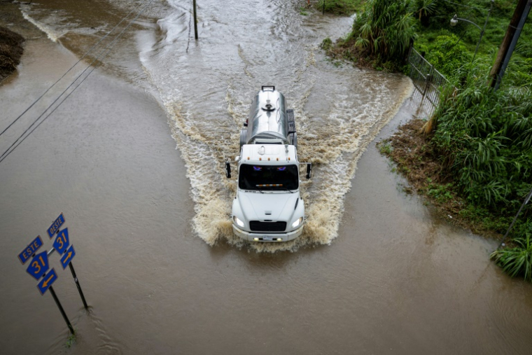 Un camion avance sur une route inondée, dans la région de Naguabo, à Porto Rico, le 16 août 2025 ( AFP / Ricardo ARDUENGO )